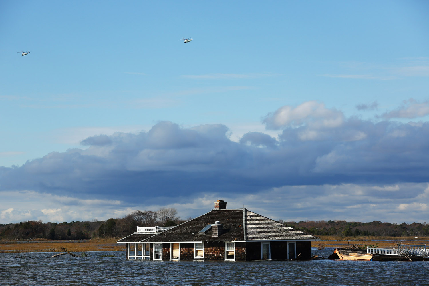Image: Oct. 31, 2012. Two helicopters fly over a house that was washed from Mantoloking into the adjacent lake some 500 yards from the closest row of houses. Mantoloking, N.J.