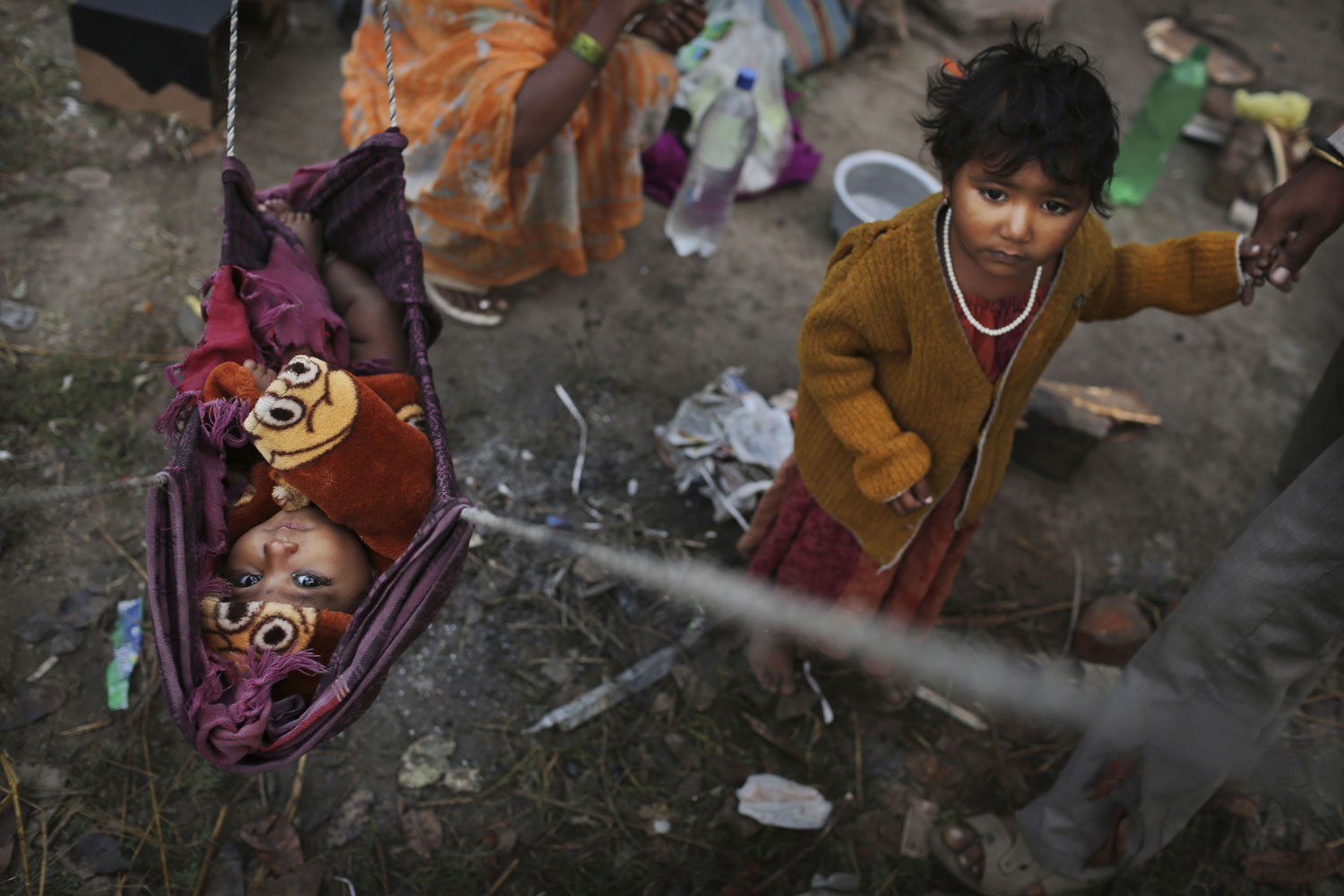 Image: Nov. 8, 2012. Indian baby Priya hangs in a makeshift bed as her sister stands next to her at a shanty where their family lives New Delhi.