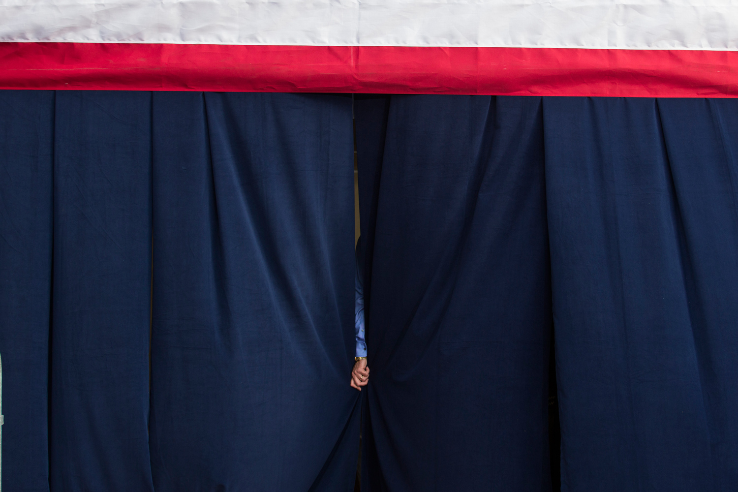 Oct. 25, 2012. A member holds a curtain backstage before the arrival of U.S. President at a campaign rally in Tampa.