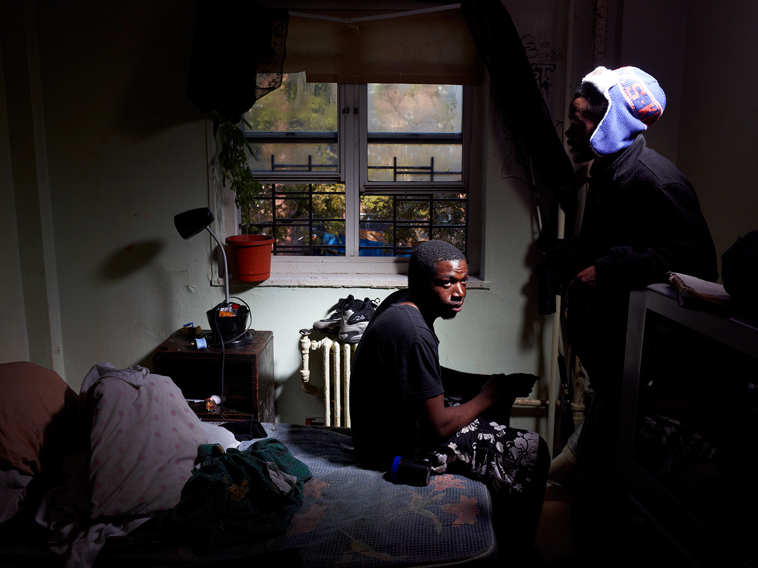 Elijah Jones, 23, sits in his room on the fourth floor of the Redfern Houses. Since the storm, water has condensed on the walls and ceiling because his room is so cold, and mold is starting to grow on his walls. Every day he tries to clean the moisture from his room, but the water keeps coming back.  That’s the only light we got,  he says pointing to a spotlight on a generator in the courtyard.  We just got that like three days ago.