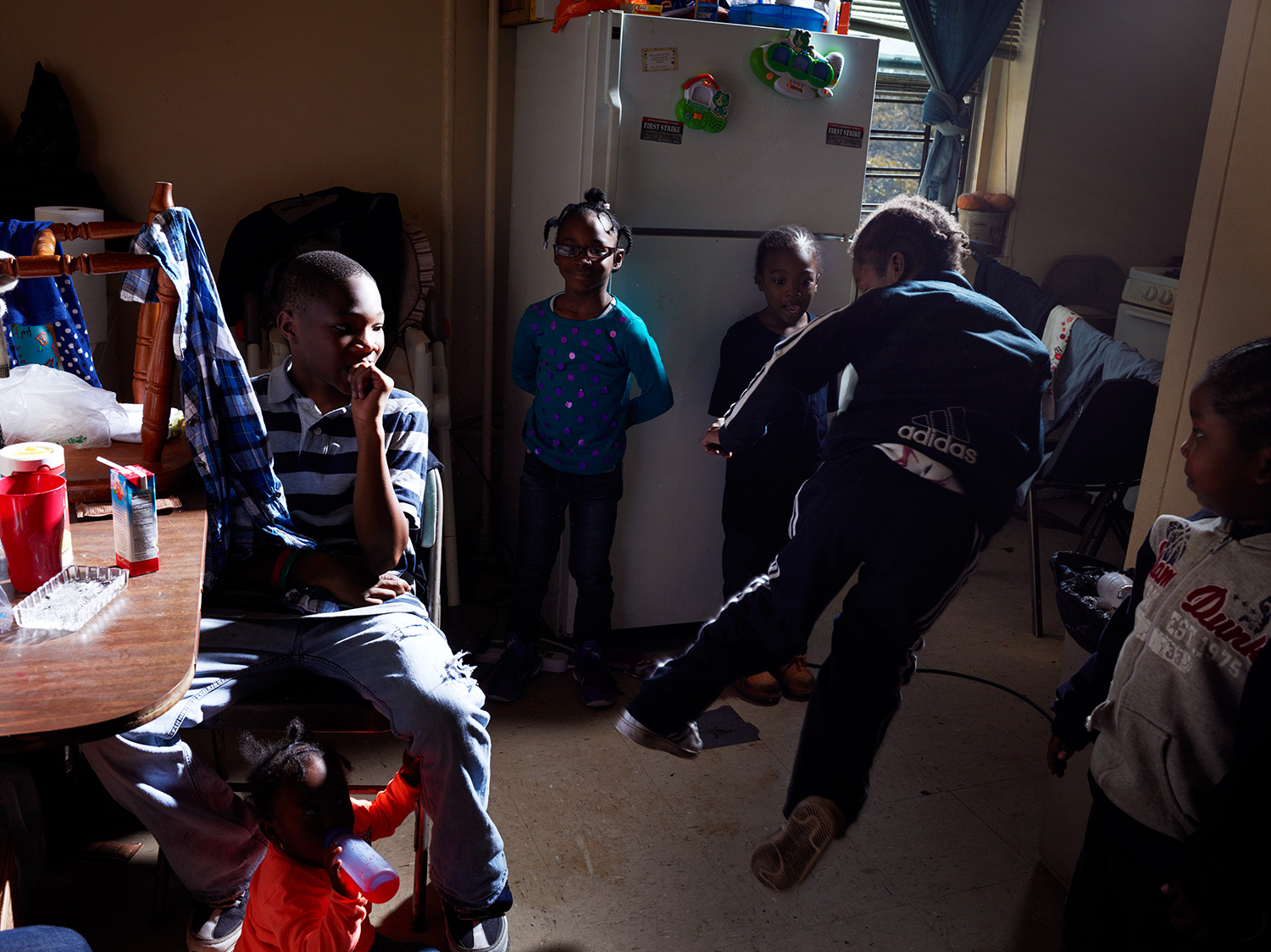 Image: Kingsley Ihim, 12; Markeya Ihim, 15 mos.; Jazzamia Ihim, 7; Martin Ihim, 4; and Shaun Ihim, 5 watch as Kebion, 6 practices his karate moves in the family’s 4th floor kitchen. "I can’t swim," says their mother, Janet, describing her plan to save her children if the flooding worsened the night of the storm. "But I have bins, so I got the bins out and I was going to out them in there and let them float to safety. Put the top on and poke a little hole for air and put their Medicaid cards in their pockets so they’d know who they are."