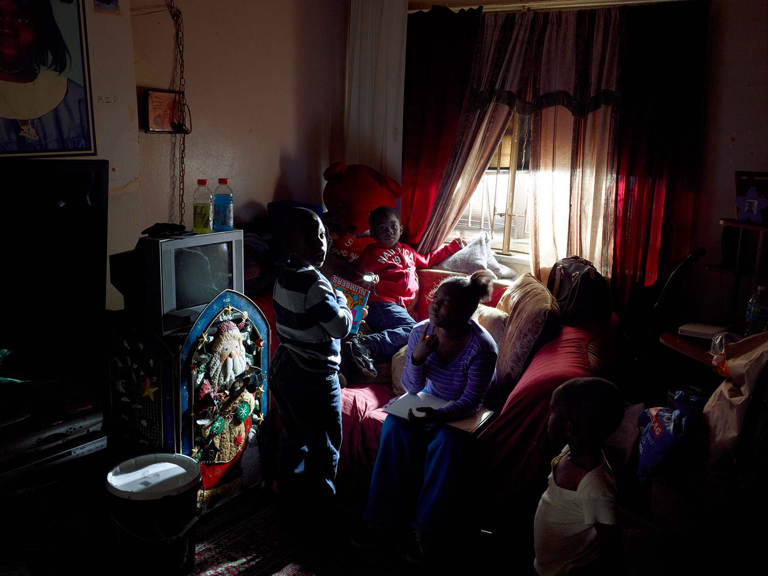 (L-R) Zaahir Graham, 5;  Khalil Holder, 4; Brianna Morris, 9; and Khasir Wright, 2 play in the living room of their grandmother, Barbara Wilson's apartment on the first floor of the Redfern Houses. When the storm hit and water came up to the window, the family ran to stay with friends on the third floor. Two weeks after the storm, the children had yet to return to school.  Thank God we’re here together,  Wilson says.  After it goes, we can always replace anything. We might be a little crazier, but we’re still here. That’s the most important thing.