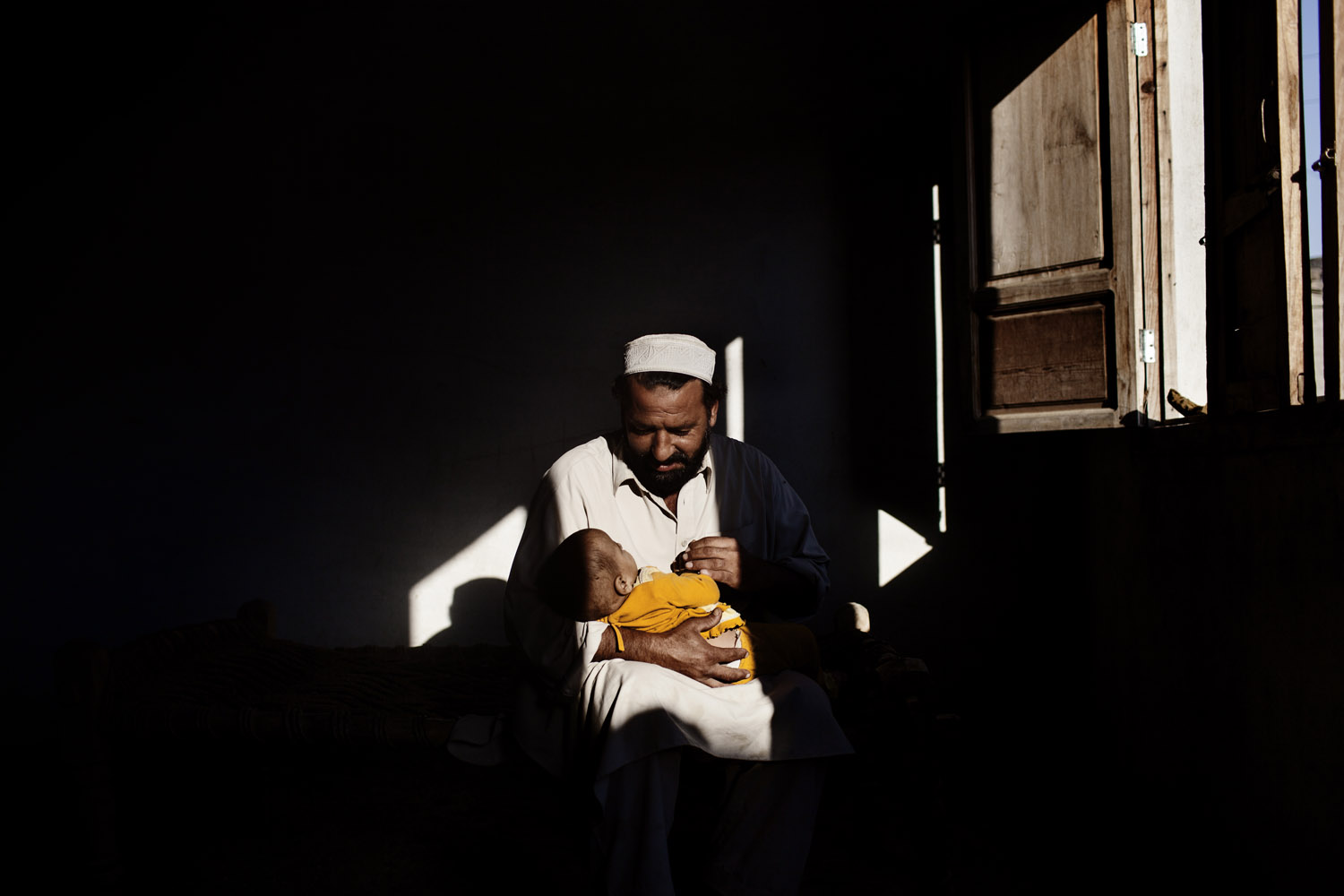 Image: A portrait of Saiful Islam holding his 8-month-daughter, Sulaim, at his home in Mardan