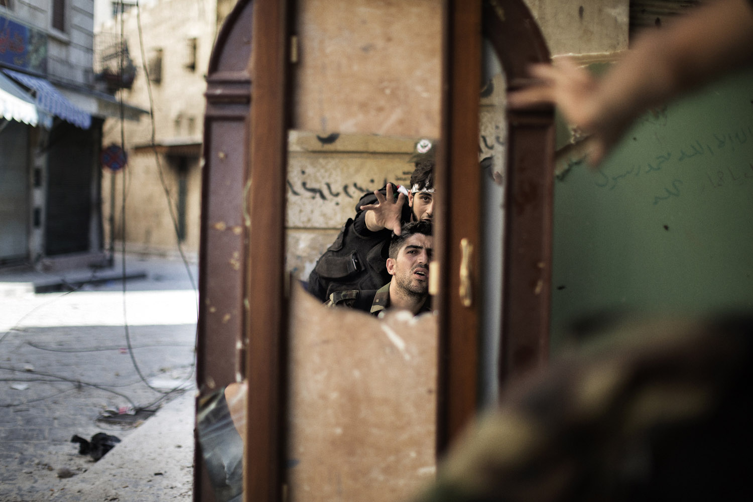 Sept. 16, 2012. Free Syria Army fighters are reflected in a mirror they use to see a Syrian Army post only 50 meters away as they man a position in the Old City of Aleppo, Syria.