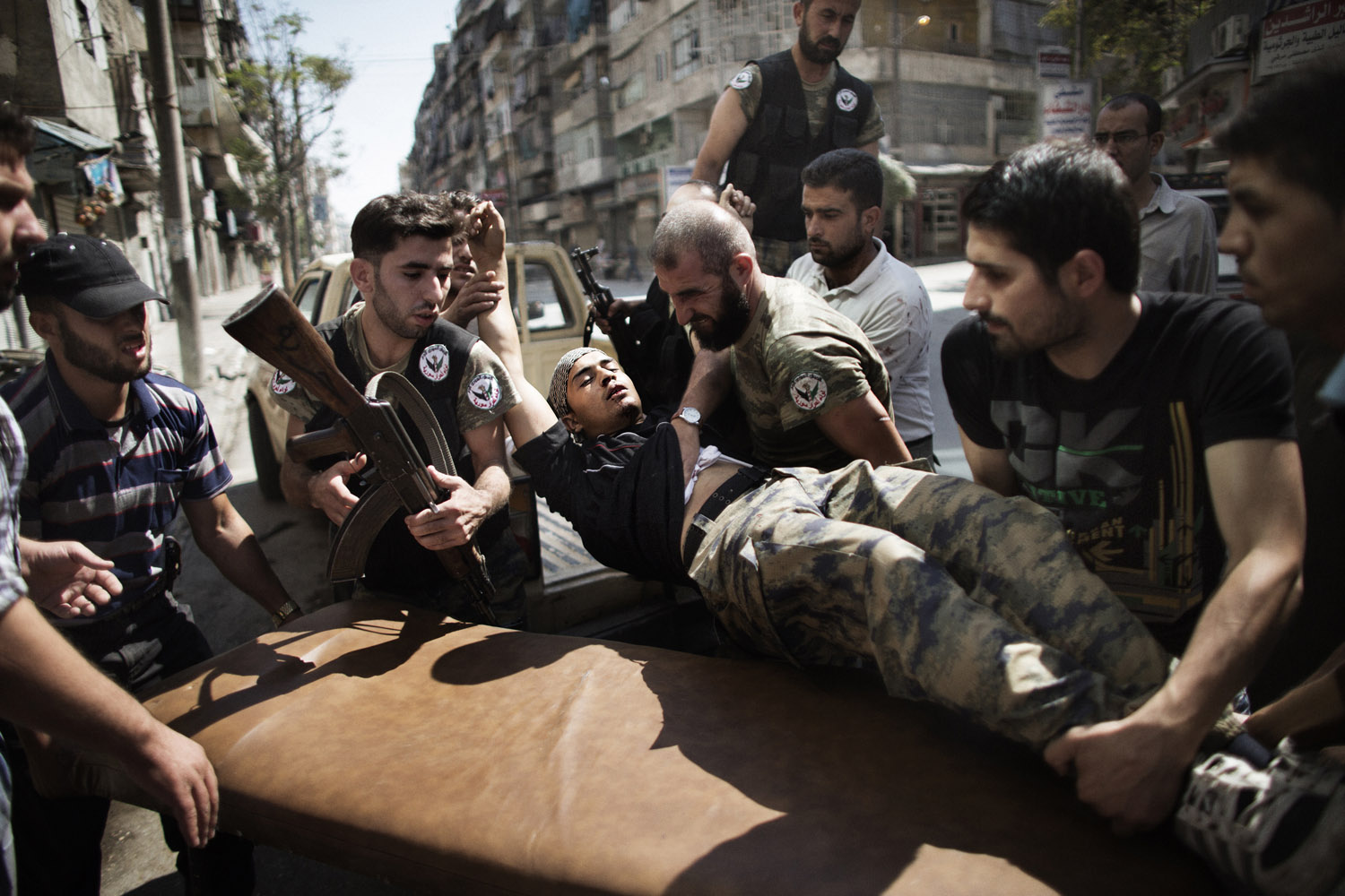 Sept. 18, 2012. Syrian rebels help a wounded comrade who survived a Syrian army strike outside a hospital in Aleppo, Syria.