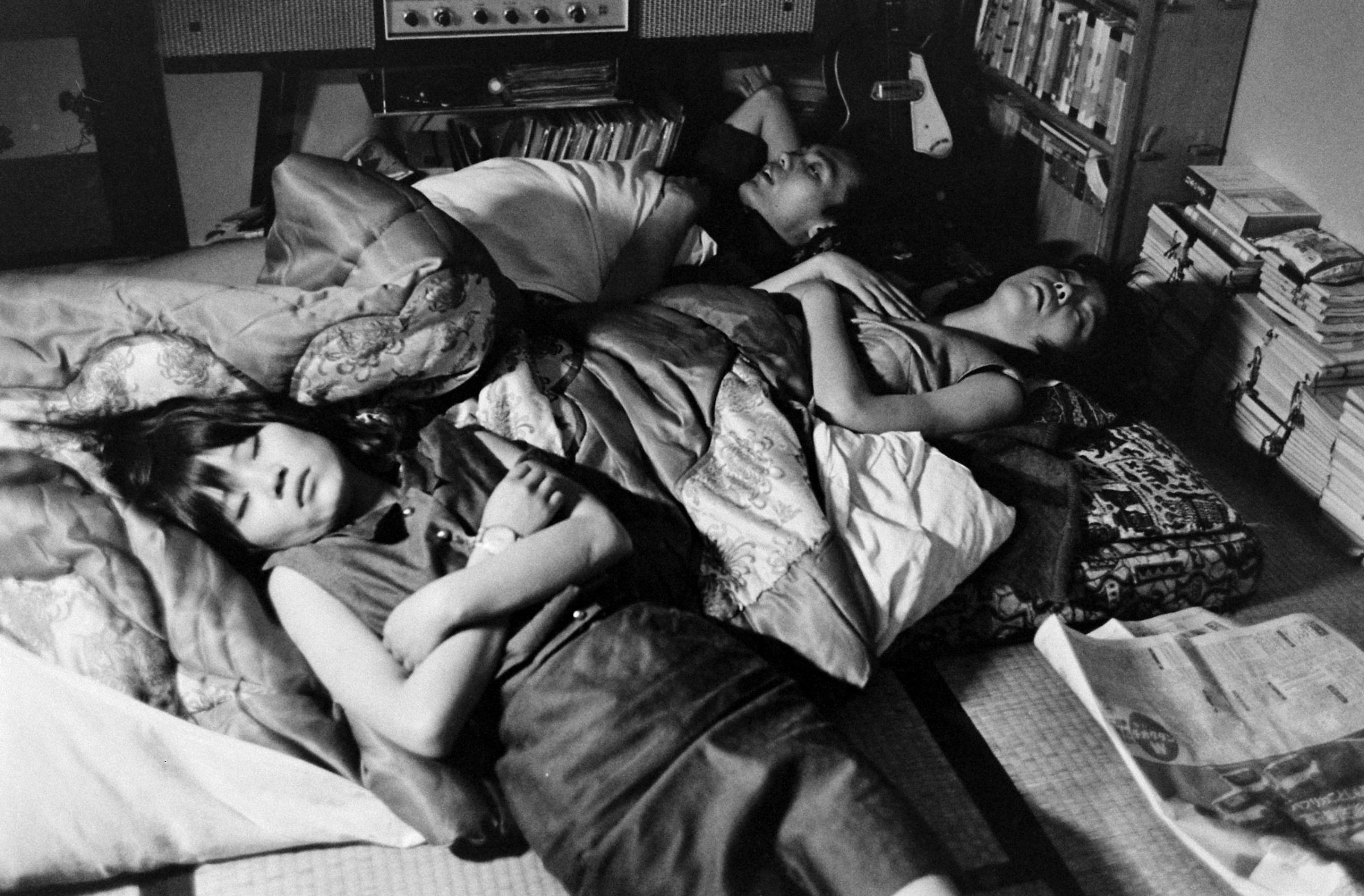 Yoko (left) ends a long night of clubbing by sleeping on a futon in a friend's room, Japan, 1964.