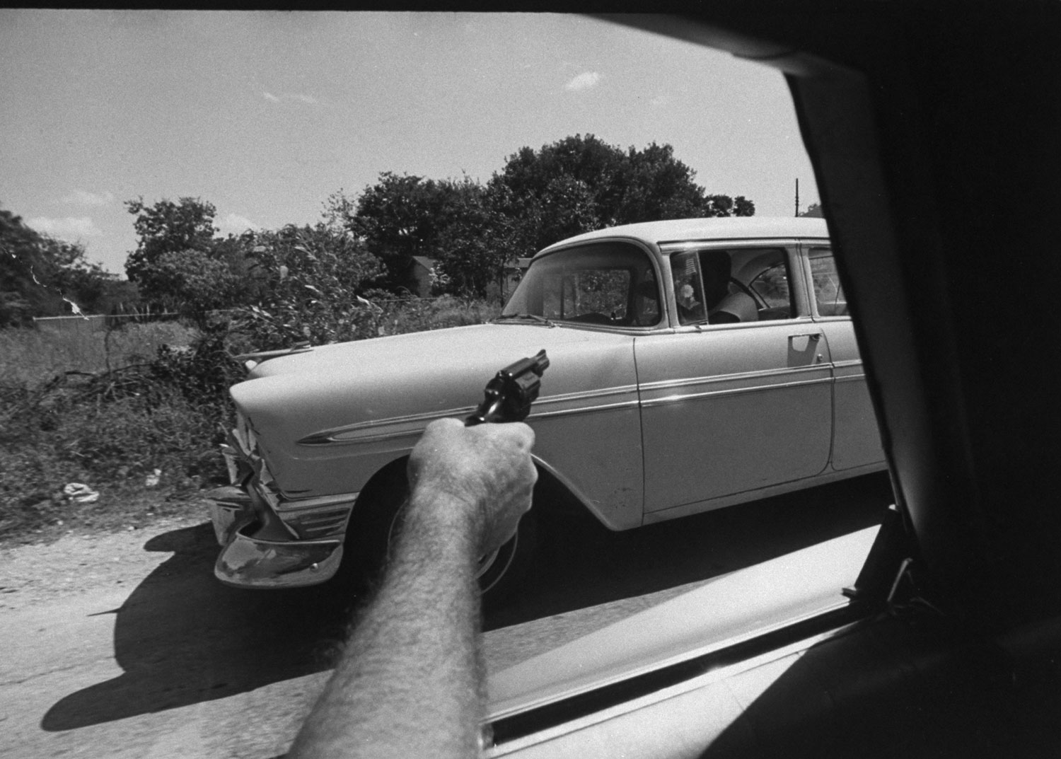 A U.S. Customs agent points his gun at a car suspected of transporting marijuana, 1969.