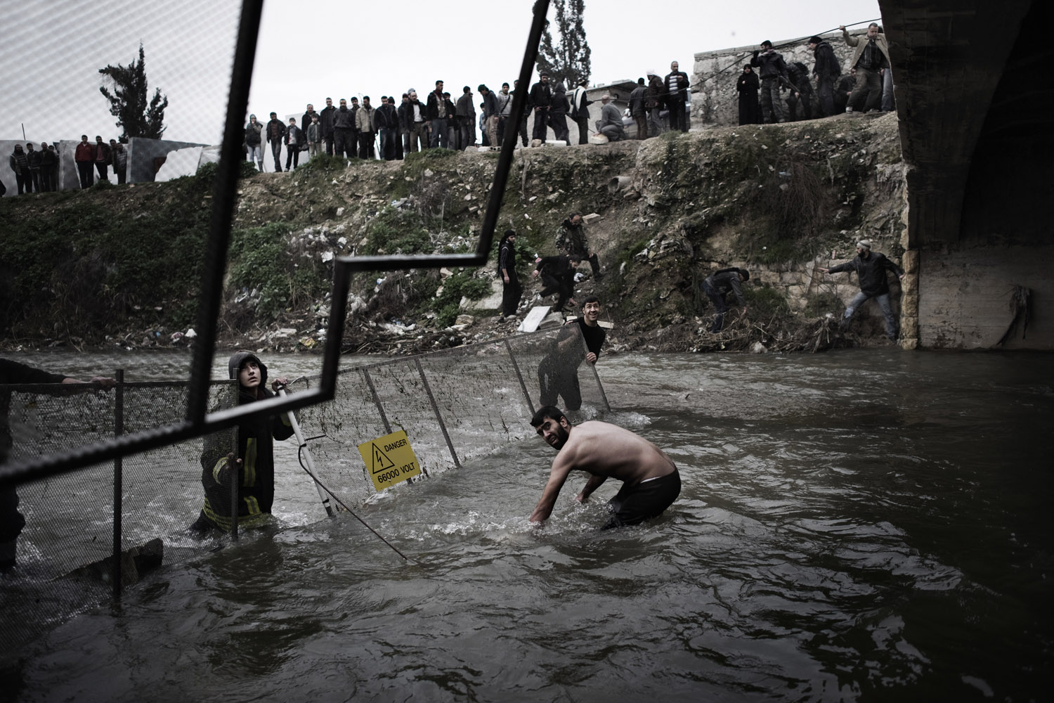 The day after victims of the massacre were first discovered, officials moved fencing into the river to help catch additional bodies as they floated downstream near Aleppo, Jan. 30, 2013. (Alessio Romenzi)