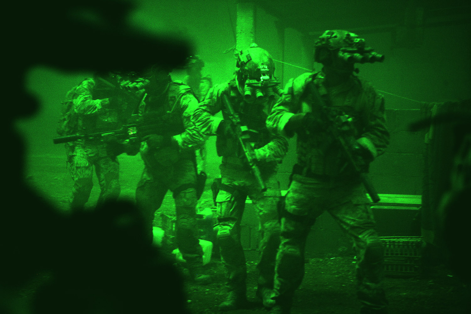 Seen through the greenish glow of night vision goggles, Navy SEALs prepare to breach a locked door in Osama Bin Laden's compound in Zero Dark Thirty.