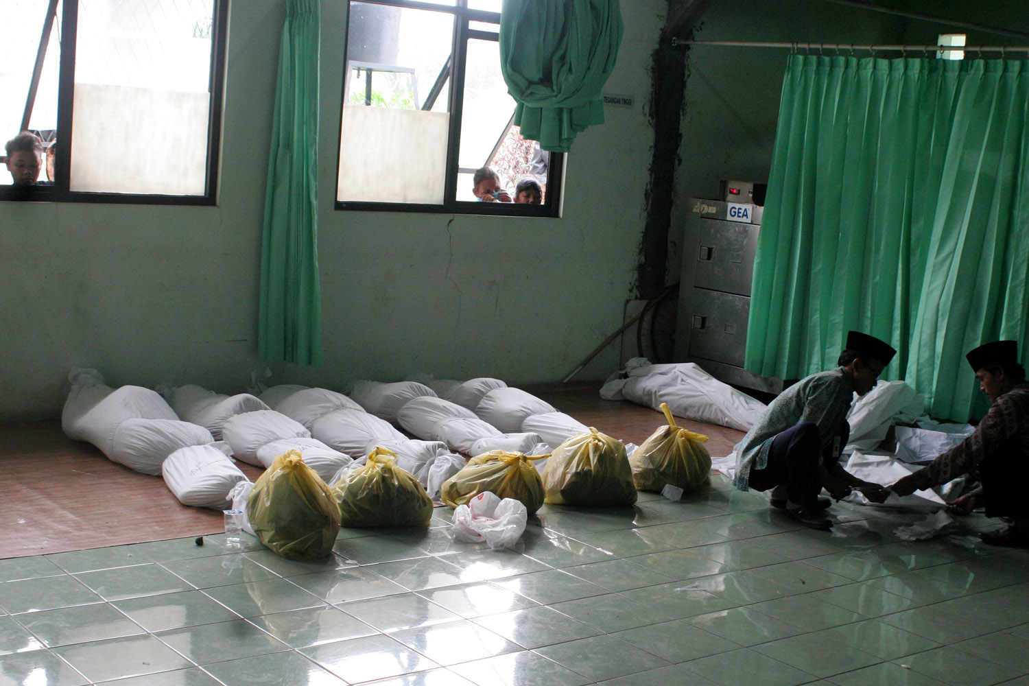 Feb. 23, 2013. Men wrap the bodies of victims of a traffic accident at the Cianjur hospital in Cianjur, Indonesia.
