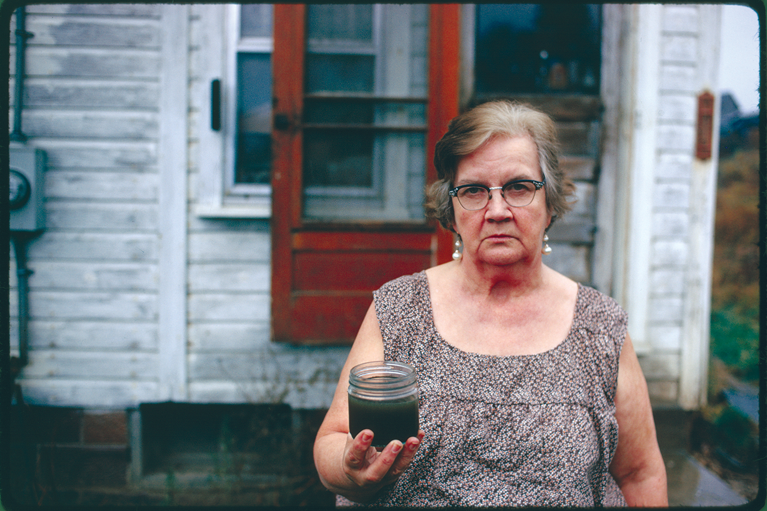 Mary Workman holds a jar of undrinkable water that comes from her well, near Stuebenville, Ohio, 1973.