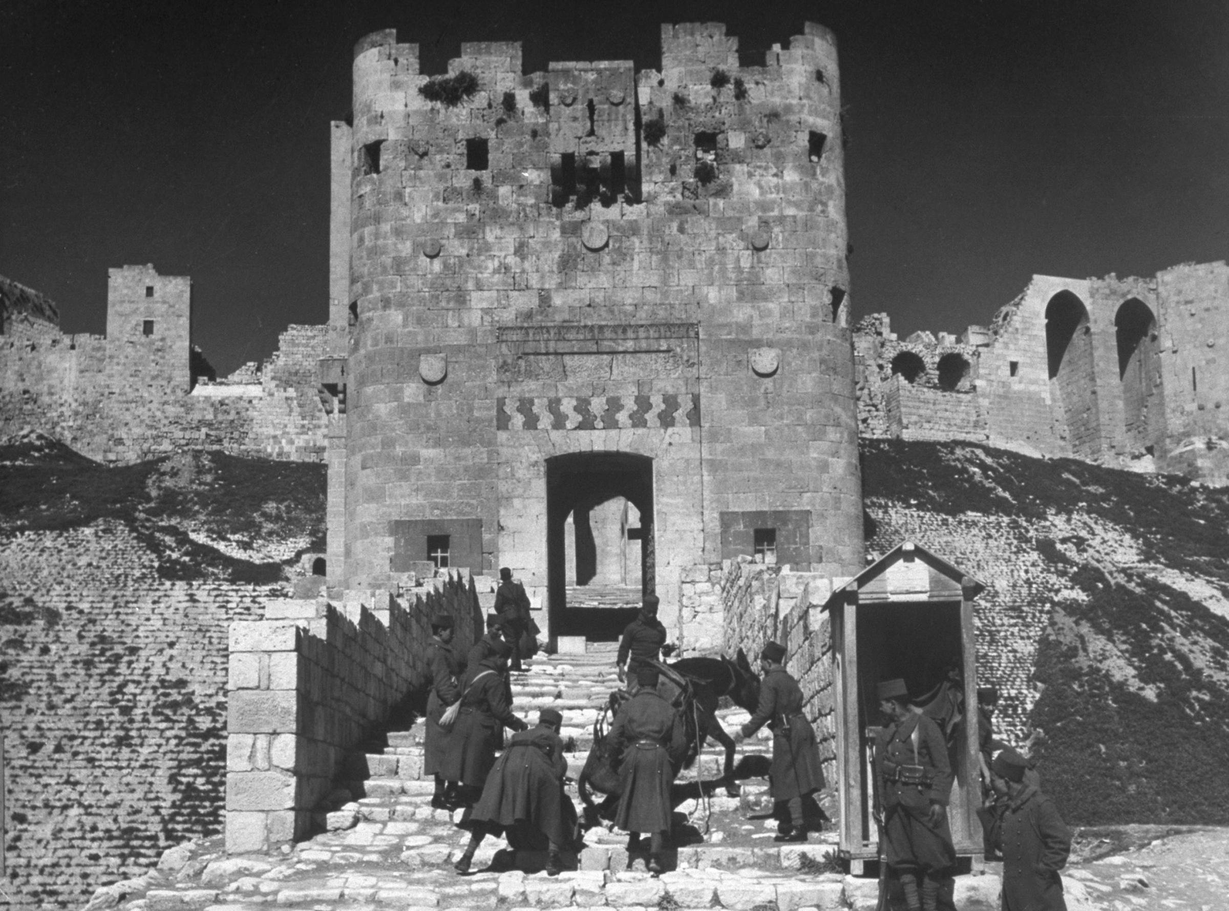 Soldiers urge a mule up the steps of the citadel at Aleppo, Syria, 1940.