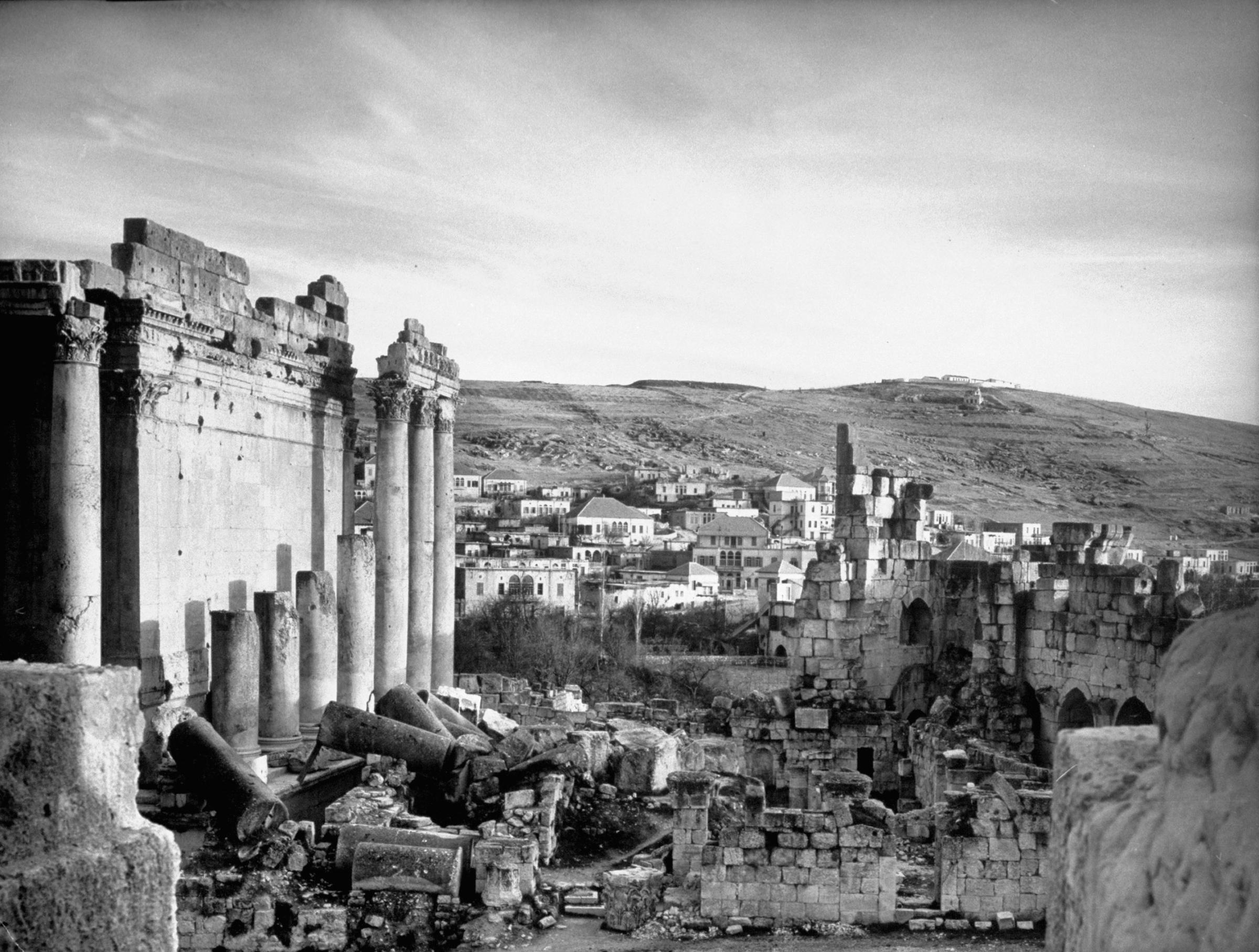 Archaeological ruins with modern homes in background, Syria, 1940.