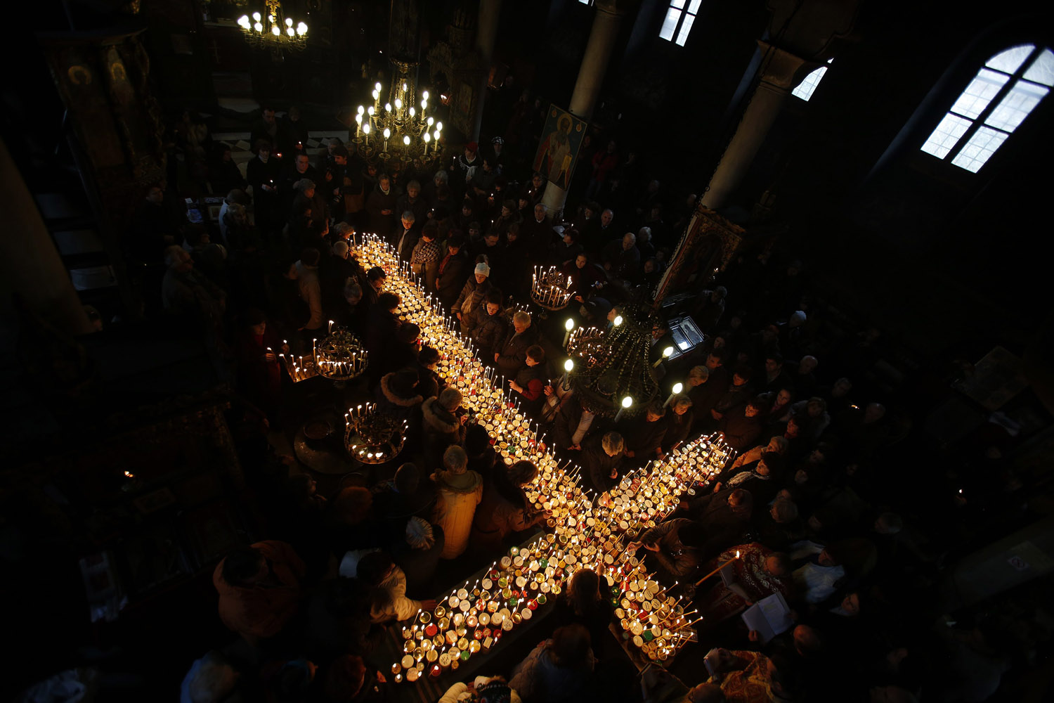 Worshippers gather around candles stuck to jars with honey, during a religious mass in the church of the Presentation of the Blessed Virgin in the city of Blagoevgrad