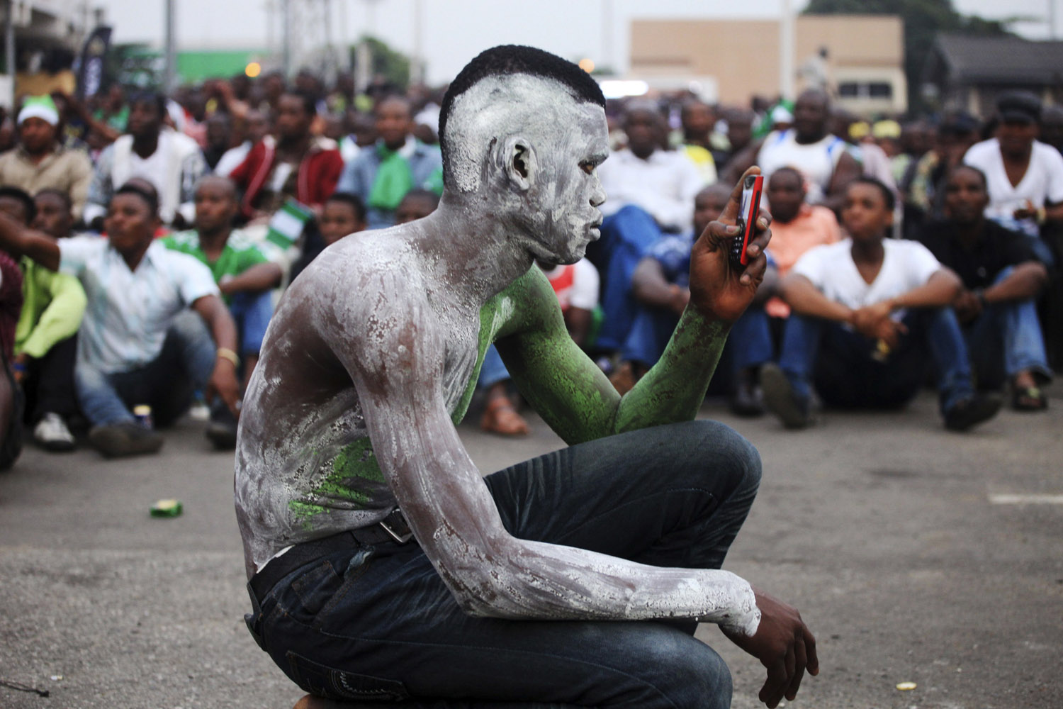 A soccer fan takes a photograph with his mobile phone at an open soccer viewing centre before the start of the Africa Cup of Nations final match between Nigeria and Burkina Faso in Lagos