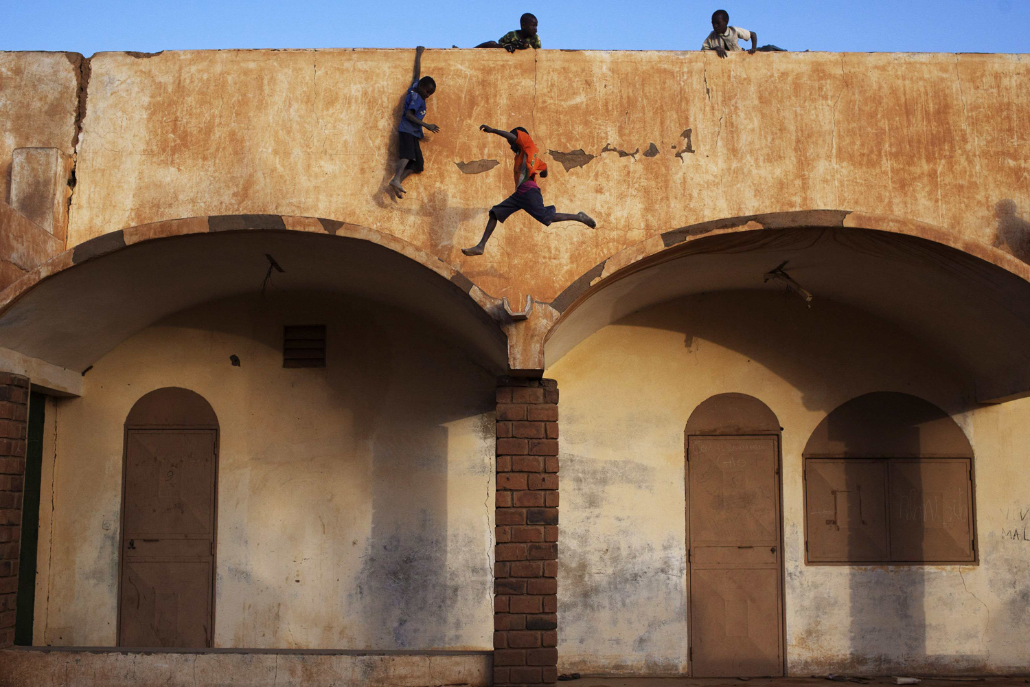 Boys play on the roof of the entrance to a football stadium in Gao