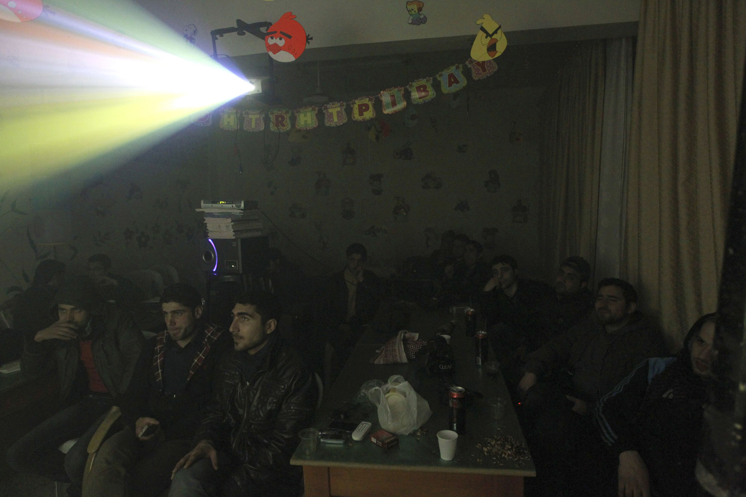 Activists watch a televised broadcast of the Champions League soccer match between Barcelona and AC Milan in a school hall in Aleppo