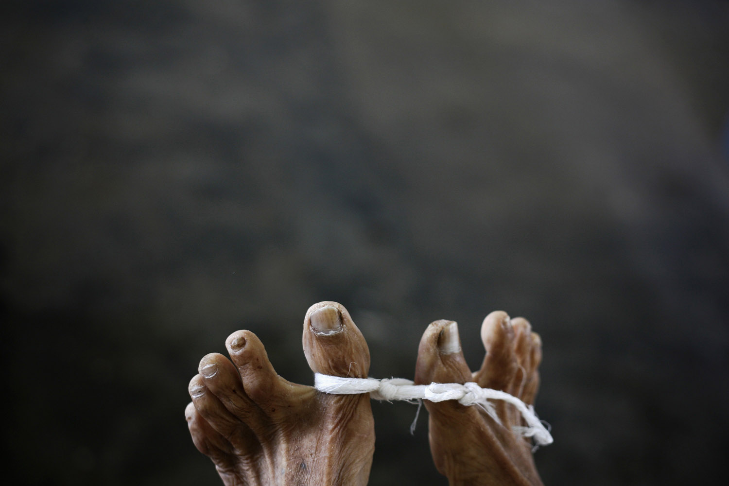 Feb. 23, 2013. The feet of U Ohn Myint, 60, who died of cancer, are tied with a piece of cloth as his body is placed inside the morgue in U Hla Tun Cancer Hospice on the outskirts of Yangon, Myanmar.