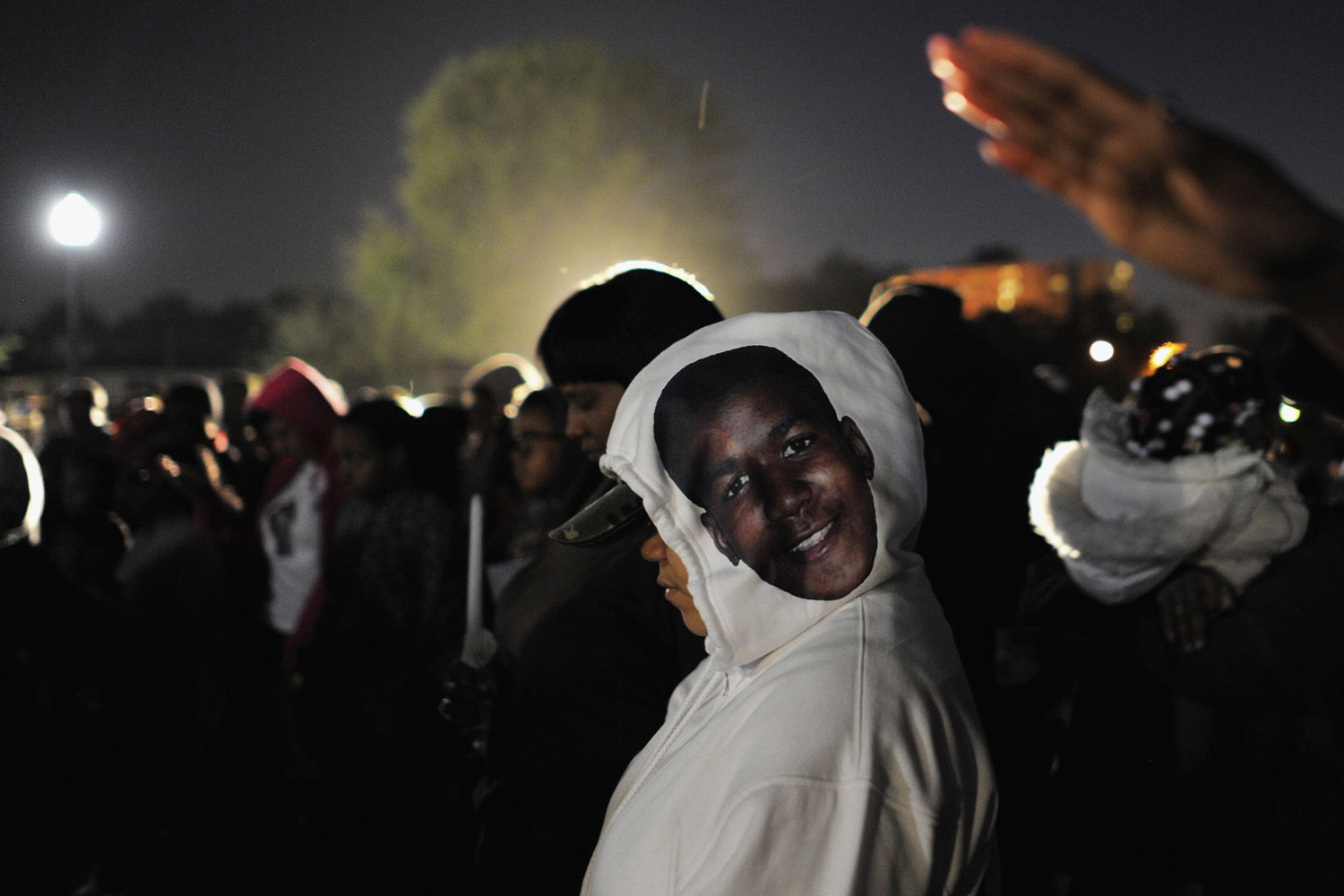 Feb. 26, 2013. A supporter wears a hooded sweatshirt with the face of teenager Trayvon Martin, as she joins other attendees in a candlelight vigil at the exact moment Martin was shot, one year ago, by neighborhood watch volunteer George Zimmerman in Sanford, Florida.