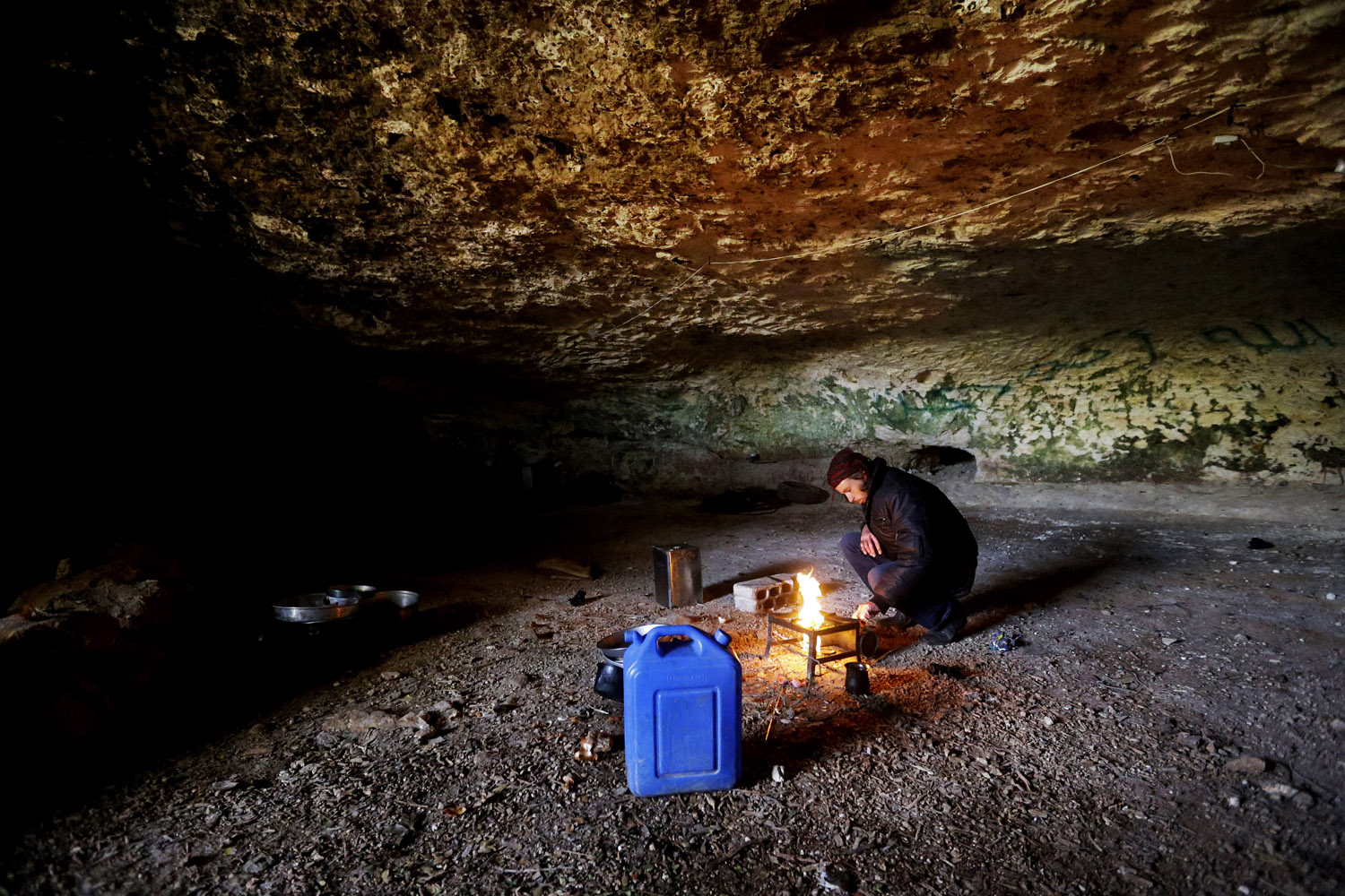 Feb. 24, 2013. A Free Syrian Army fighter prepares a fire to cook, inside a cave at Jabal al-Zaweya, in Idlib, Syria.