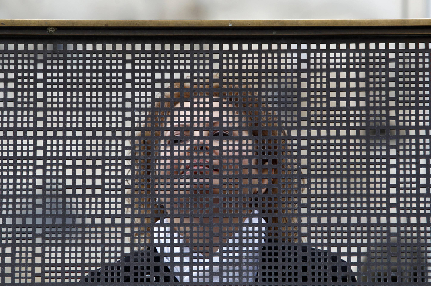 A woman stands behind a metal screen at the Western Wall in Jerusalem's Old City