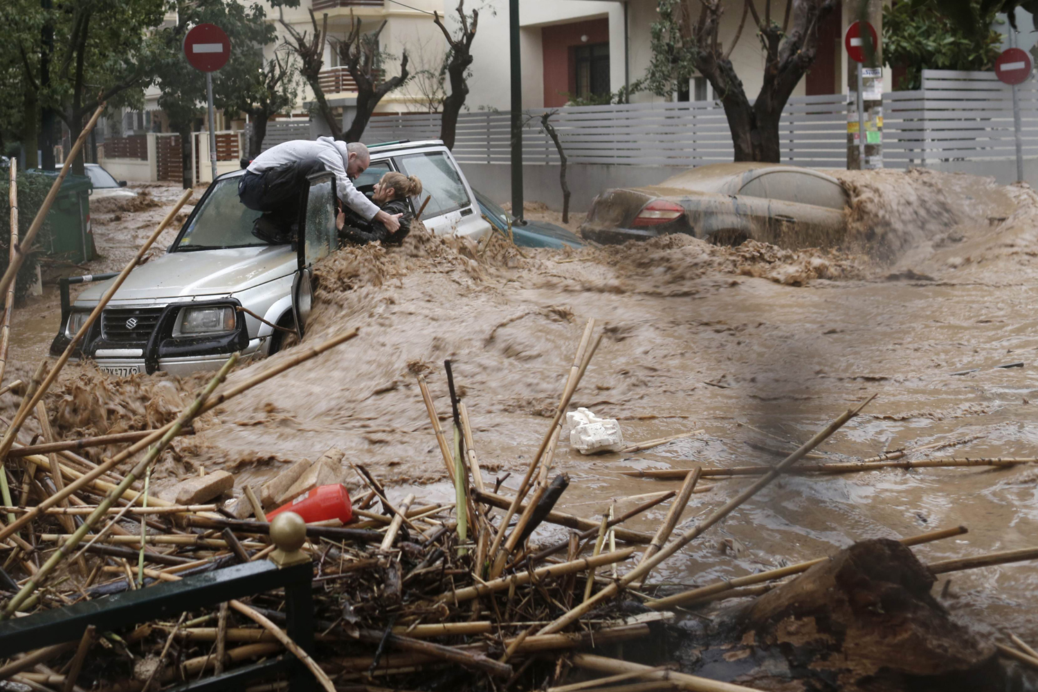 A woman is rescued from flood waters by a resident standing on top of her car during heavy rain in Chalandri suburb north of Athens
