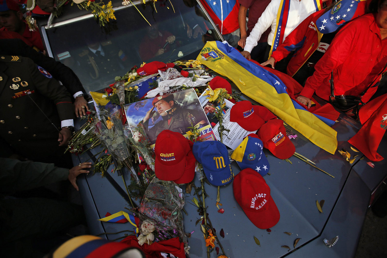 Caps and posters of late Venezuelan leader Hugo Chavez lie on the hood of the hearse that carried his coffin in Caracas