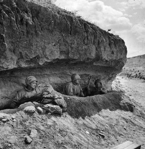Three tank-destroyer men take refuge in foxholes under a bank during a Stuka bombing attack. U.S. tank destroyers, with 3-inch guns, played a big part in defeat of 10th Panzers, Tunisia, 1943.