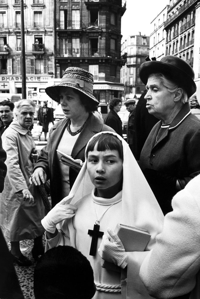 Parisian girl dressed for her first communion accompanied by family members, 1963.