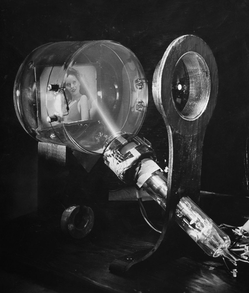 Laboratory scene of how television works, showing the image of a girl being focused through a lens onto a sensitive plate as an electron beam (its path shown by glowing gases) scans it, 1944.