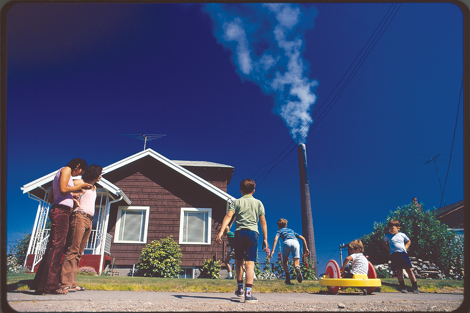 Children play in yard of Ruston home, while Tacoma smelter stack showers area with arsenic and lead residue. Washington State, 1972.