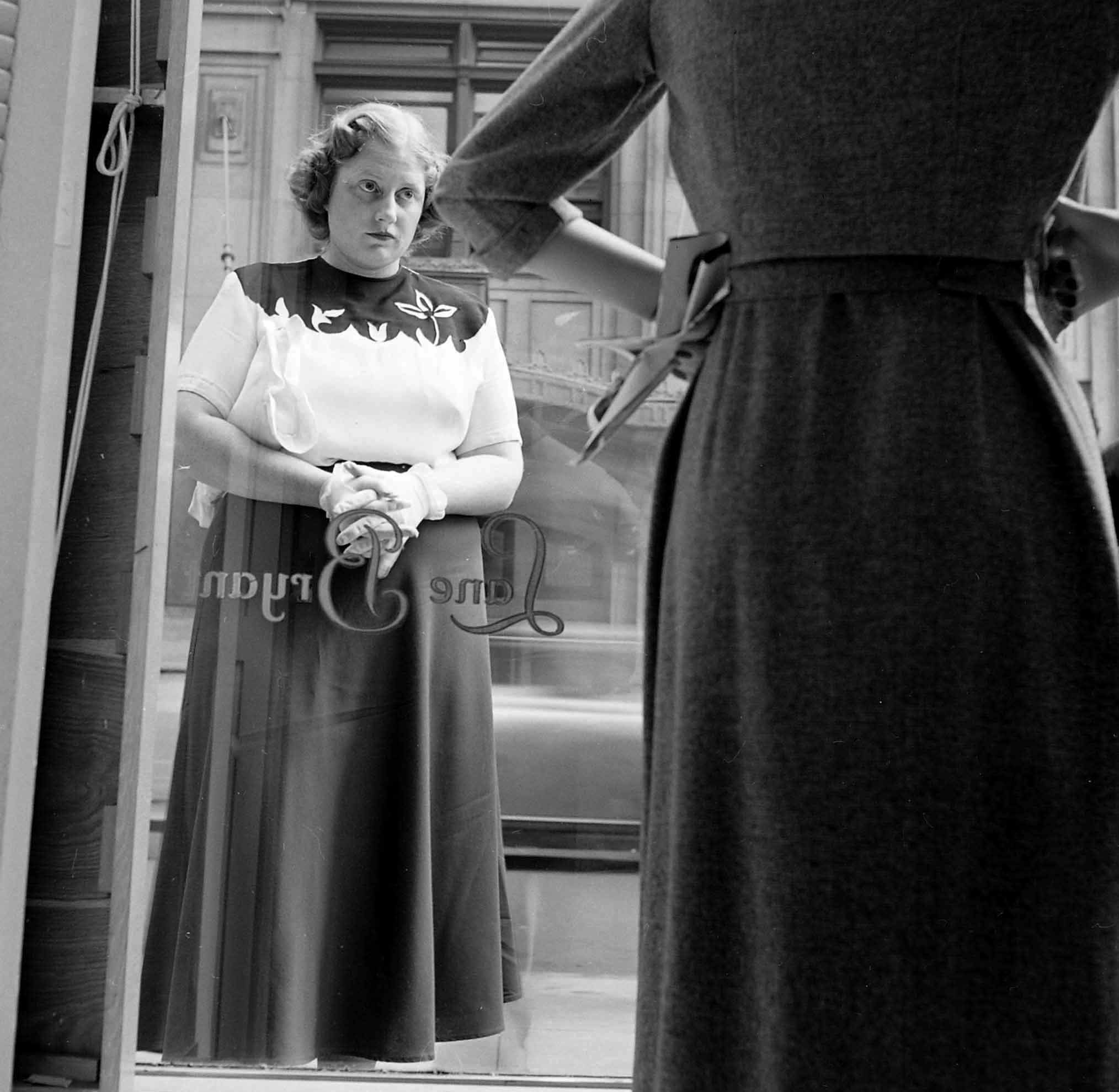 Dorothy Bradley, photographed for LIFE magazine article on obesity, eyes dress in a store window, 1949.
