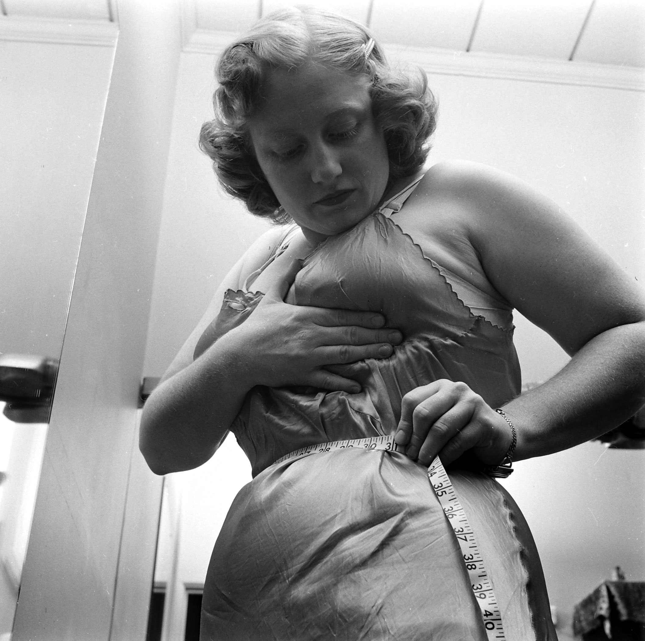 Dorothy Bradley, photographed for LIFE magazine article on obesity, measures her waist, 1949.