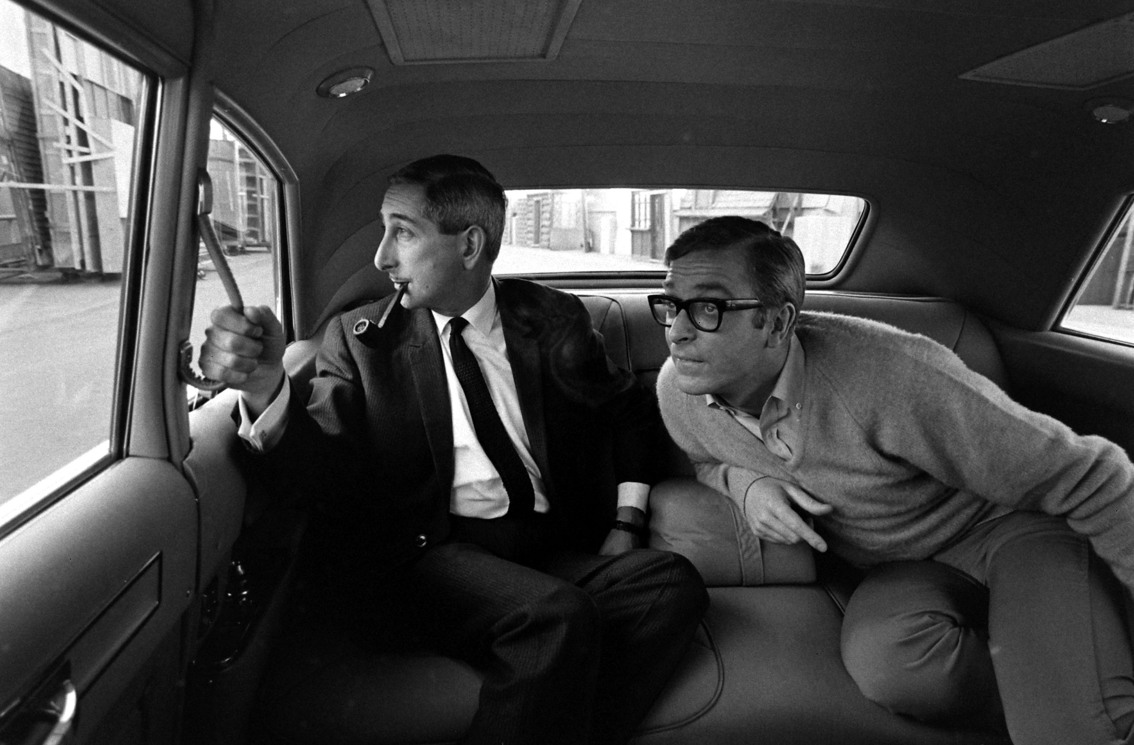 Michael Caine and an unidentified man in a car in Los Angeles in 1966.