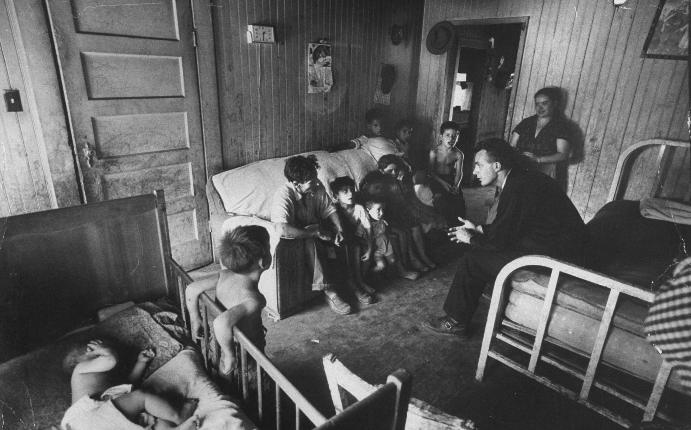A priest and workers' rights activist speaks with a migrant worker's family in Stockton, California, 1959.