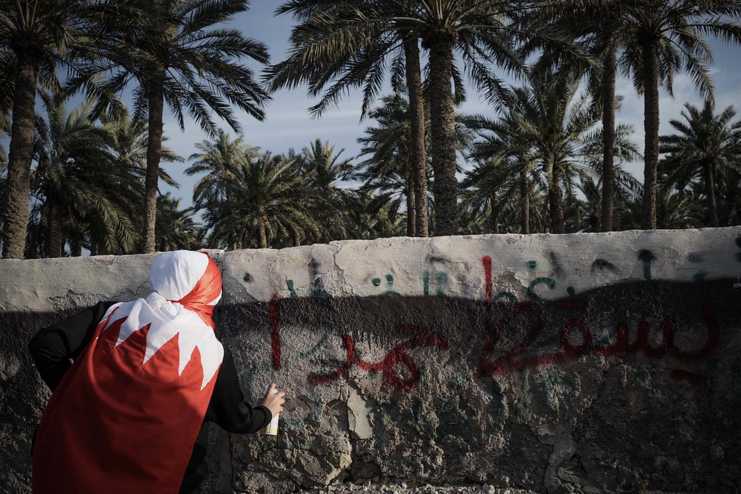 March 22, 2013. A Bahraini woman writes a graffiti reading in Arabic  Down with Hamad during an anti-government rally in solidarity with jailed human rights activist, Nabeel Rajab in the village of Belad Al Qadeem, in a suburb of Manama. The International Federation for Human Rights says around 80 people have been killed in Bahrain since violence first broke out on February 14, 2011 when thousands of protesters camped out in Manama's Pearl Square, taking their cue from the Arab Spring uprisings.