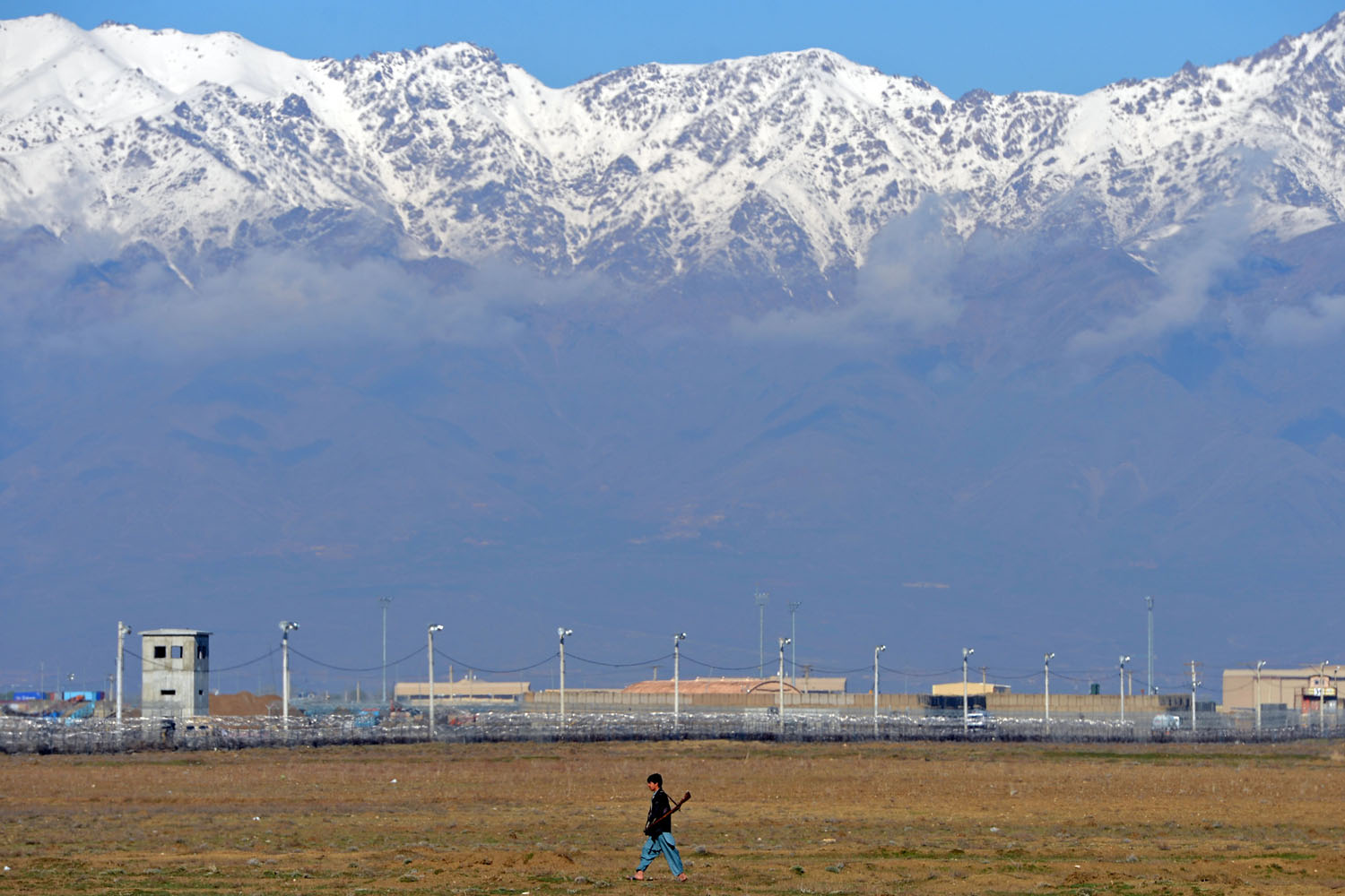 March 25, 2013. An Afghan man carries an old gun as he walks past Bagram Prison facilities outside Kabul. Afghanistan on Monday took full control of Bagram prison from the United States, healing one running sore in their testy relationship as US-led forces wind down more than a decade of war.