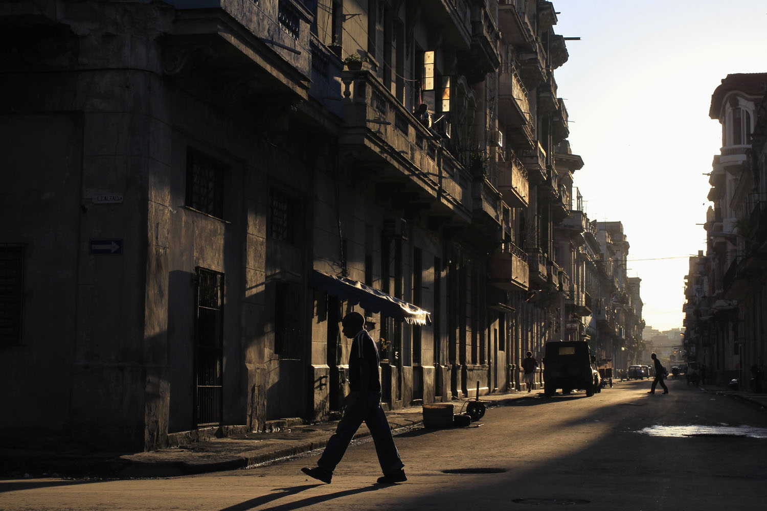 People are silhouetted as they walk along a street in Havana