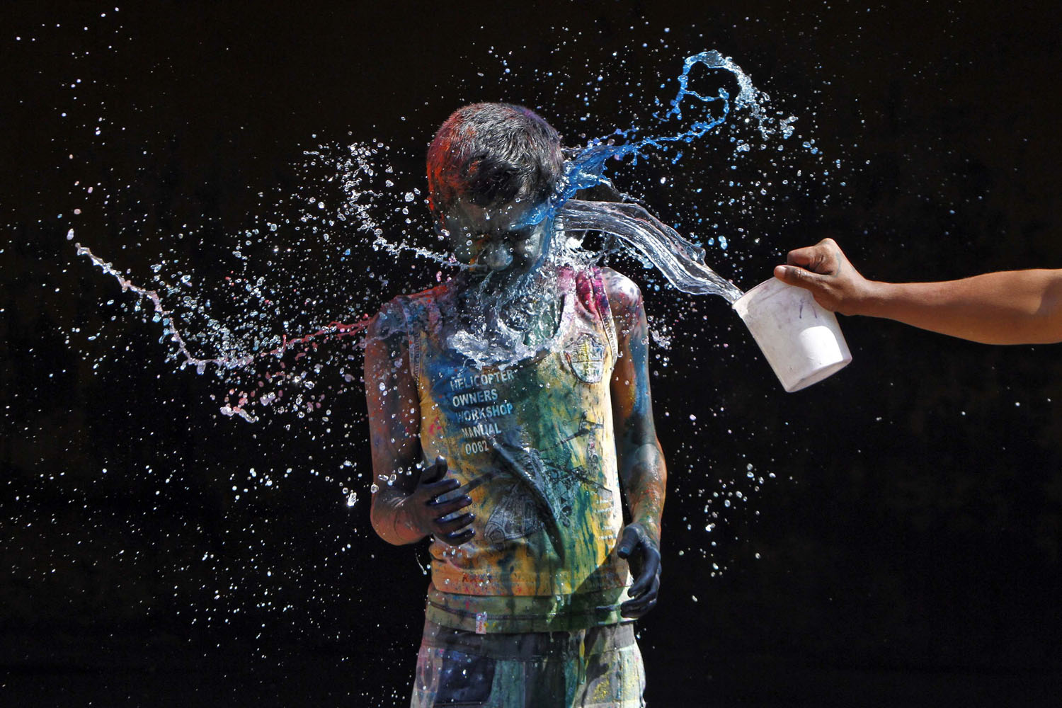 March 27, 2013. A boy smeared with colors reacts as another boy pours water on him during Holi celebrations in the southern Indian city of Chennai.