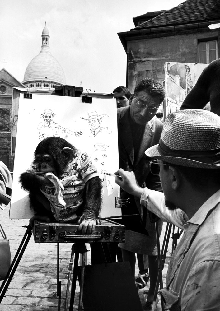 Montmartre sidewalk artist and monkey entertaining tourists in the Place du Terte near Sacre Coeur, 1963.