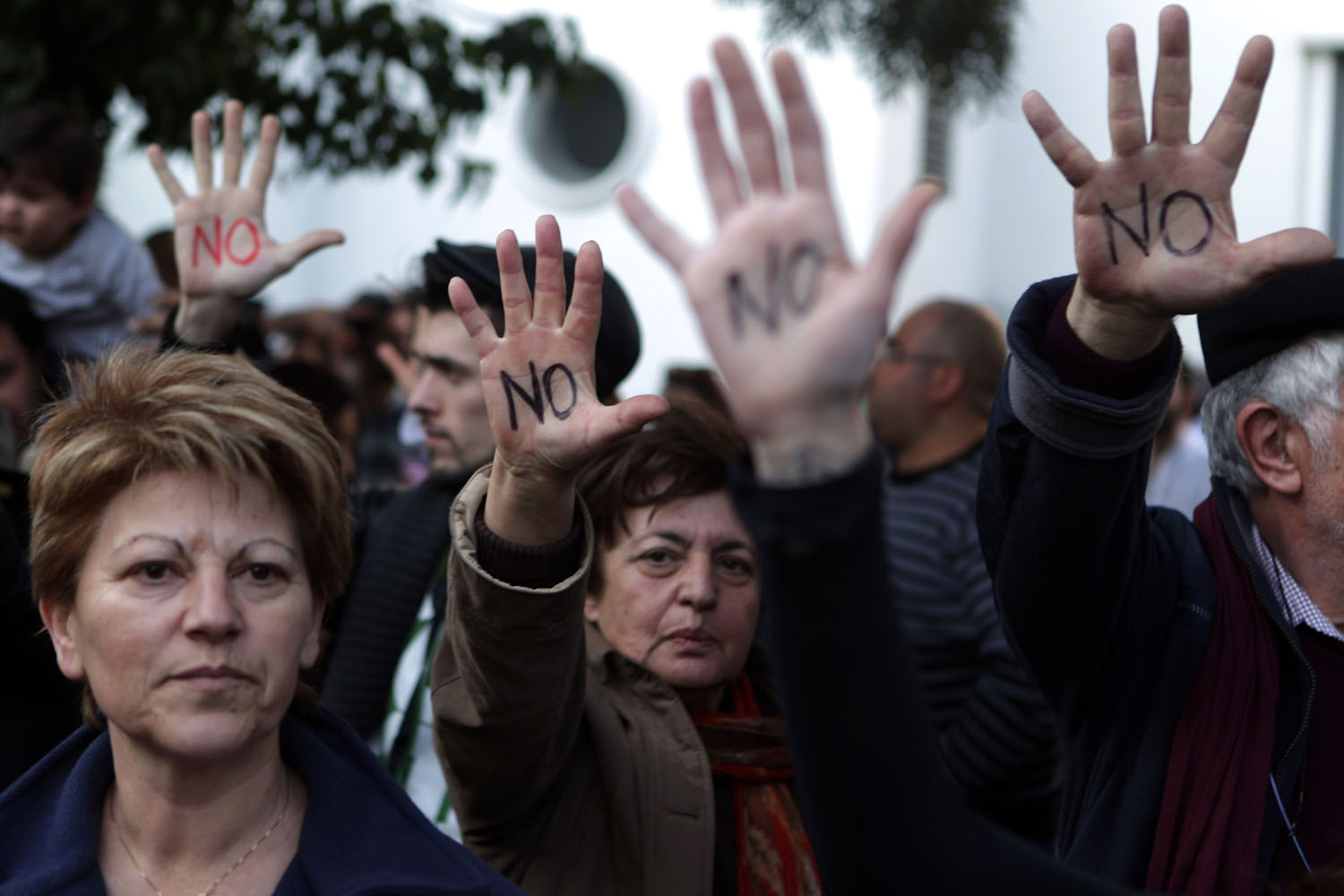 Cypriots show their palms reading "No" during a protest against an EU bailout deal outside the parliament in Nicosia.