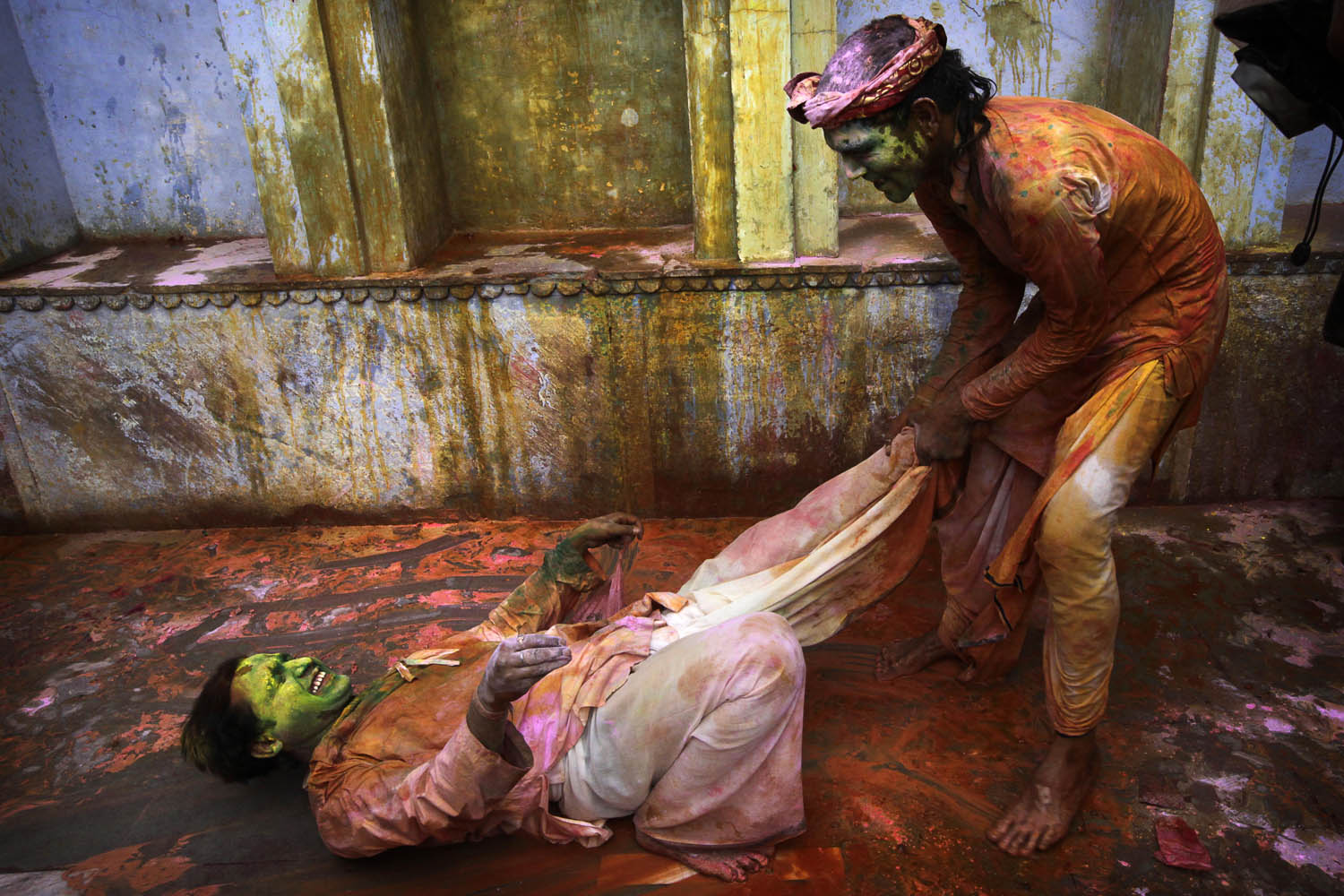 March 22, 2013. Indian Hindu devotees smeared with colors play  at the Nandagram temple famous for Lord Krishna and his brother Balram, during Lathmar holy festival, in Nandgaon 120 kilometers ( 75 miles)  from New Delhi, India. During Lathmar Holi the women of Nandgaon, the hometown of Krishna, beat the men from Barsana , the legendary hometown of Radha, consort of Hindu God Krishna , with wooden sticks in response to their teasing as they depart the town.