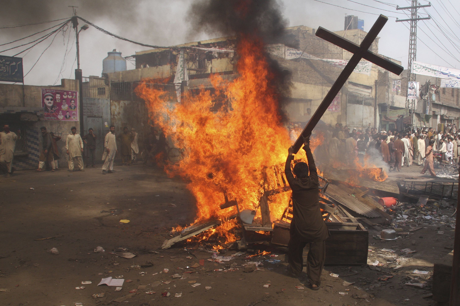 A demonstrator burns a cross during a protest in the Badami Bagh area of Lahore