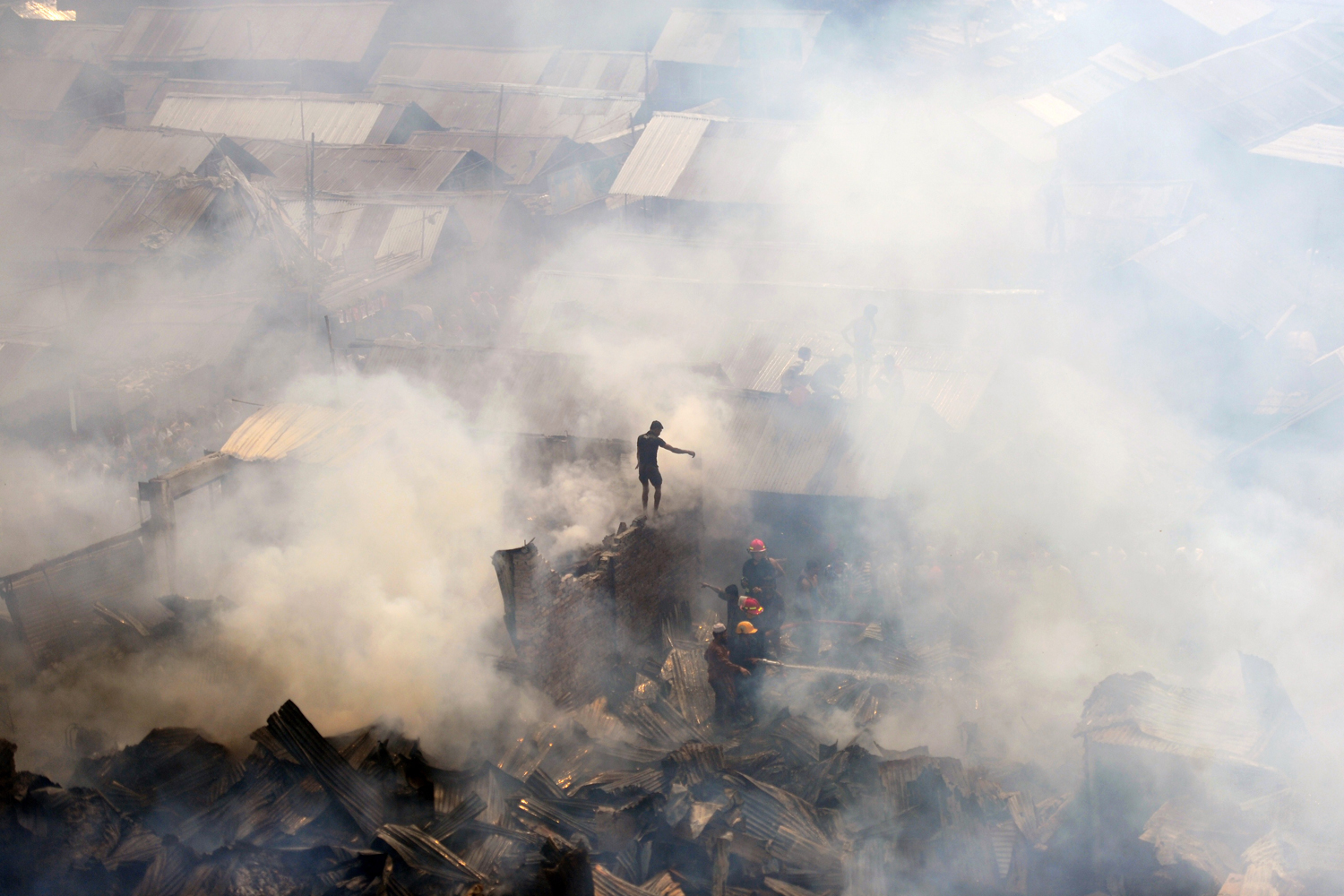 Feb. 27, 2013. Bangladeshi firefighters try to control a blaze at a slum in Dhaka. At least 300 shanties were gutted but no casualties were reported.