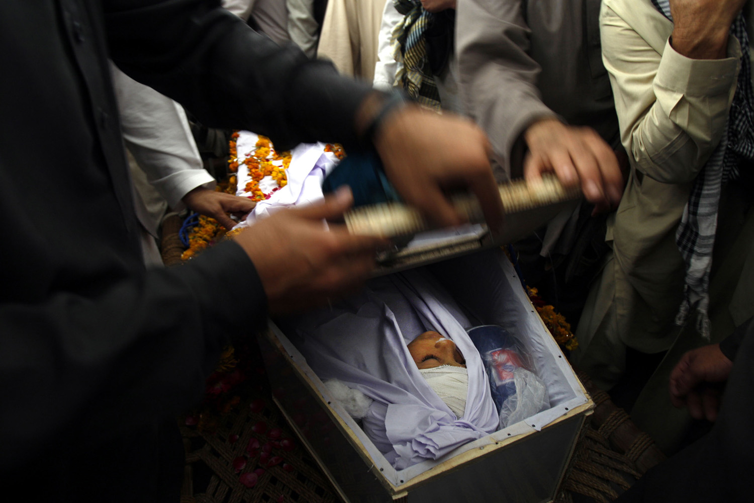 April 17, 2013. Pakistani villagers look at a victim from last night's suicide attack, during a funeral procession in Peshawar on Wednesday.