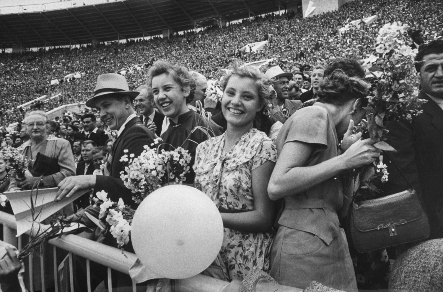 Crowd at Lenin Stadium during a sports festival, with some holding flowers for the winning athletes, 1956.