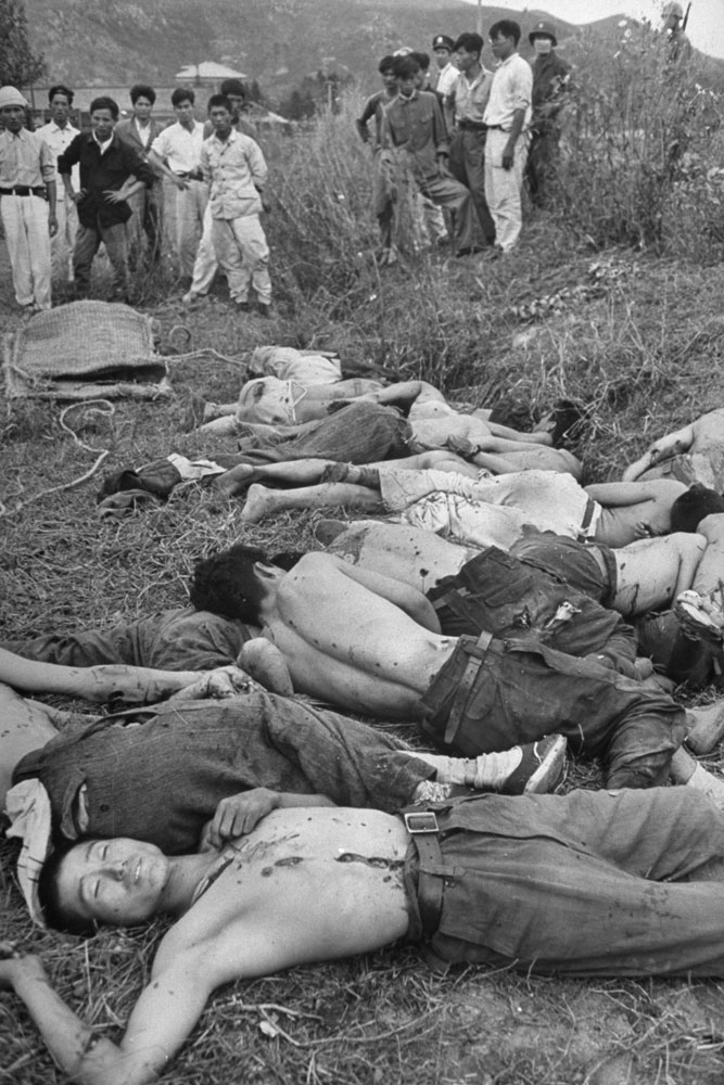 Dead rebels, their bodies dotted with bullet holes, lie beside a school ground at Sunchon.