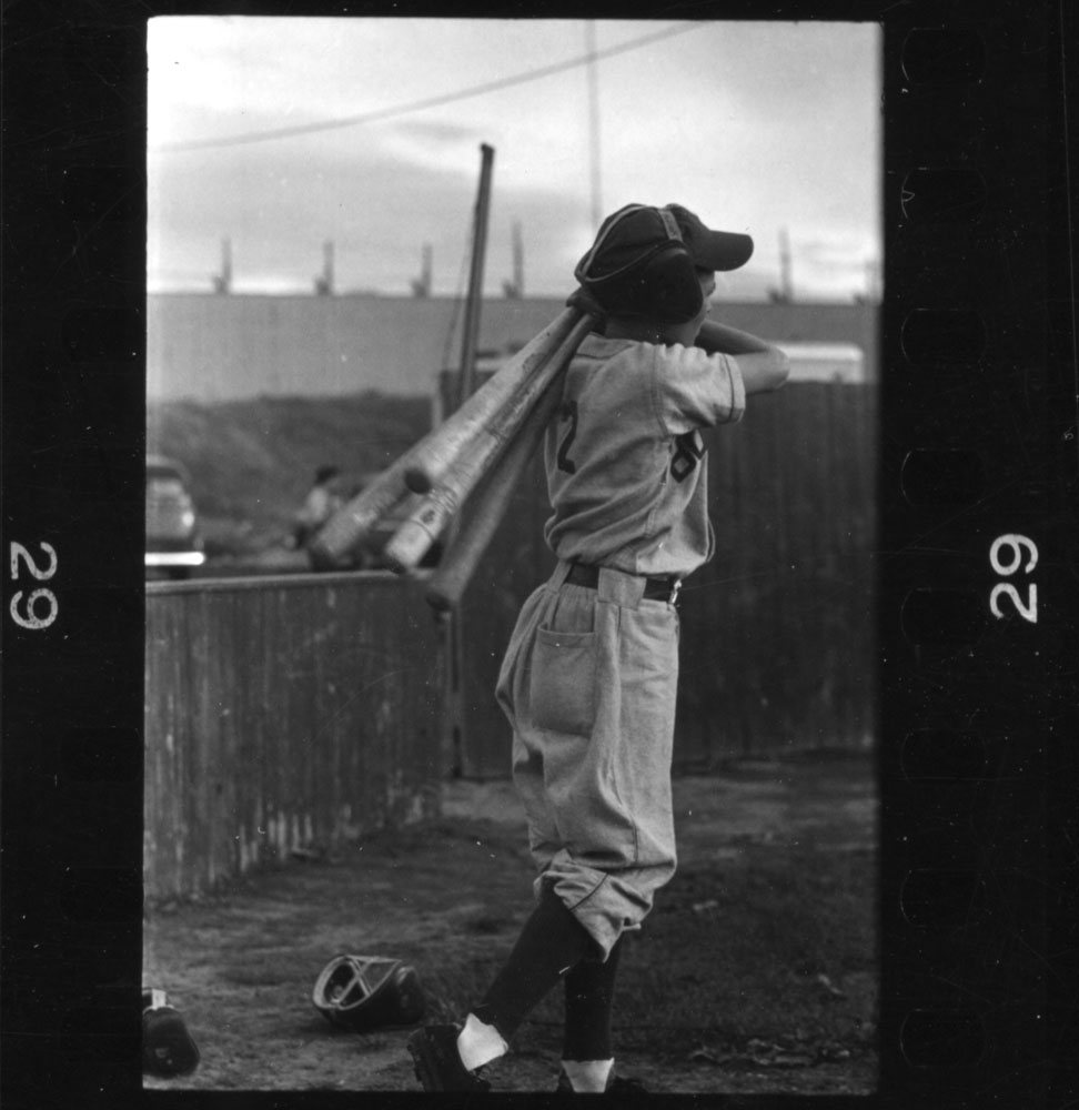 Boy carrying baseball bats, New Hampshire, 1954.