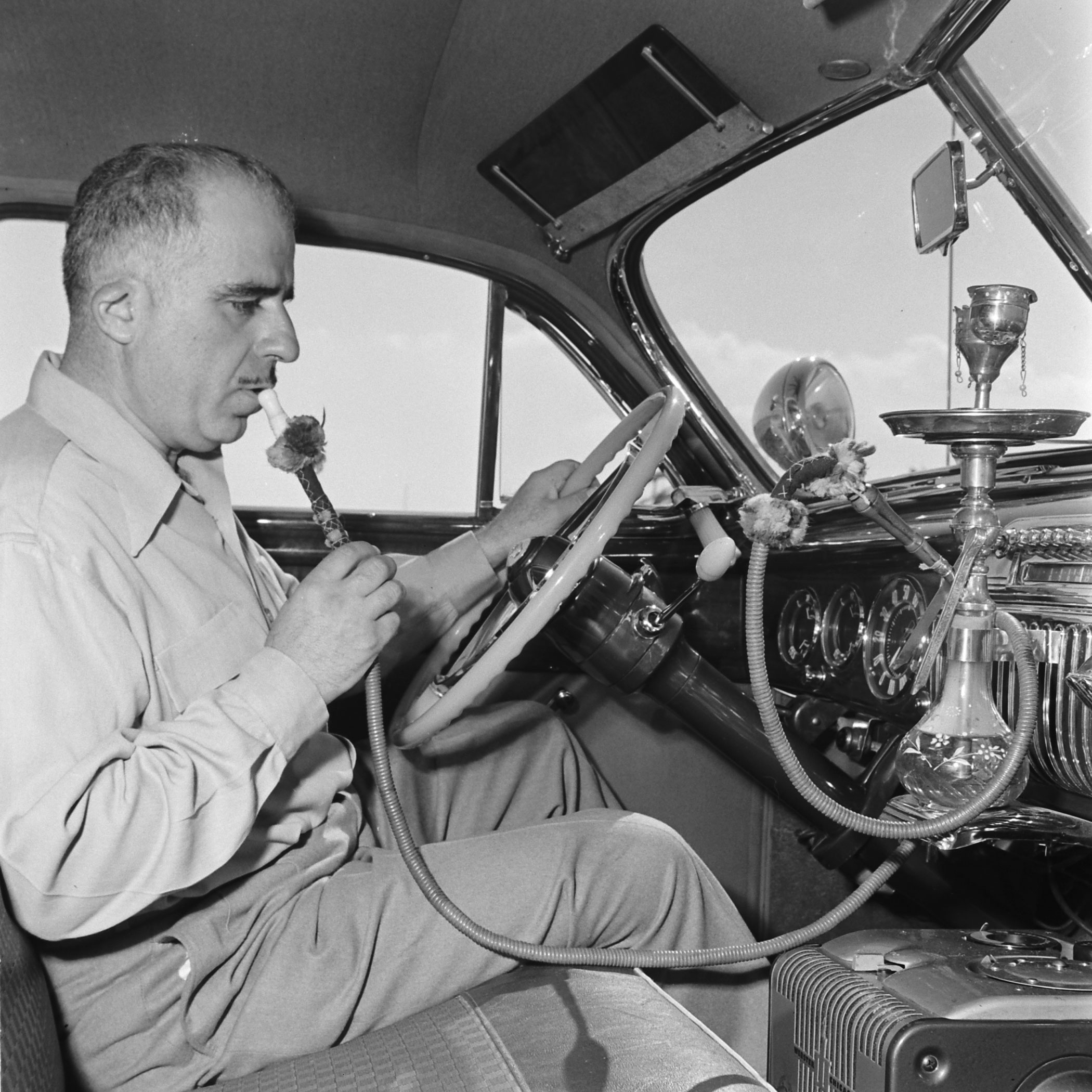 Louis Mattar enjoys a pull on the water pipe he installed in his heavily modified 1947 Cadillac.