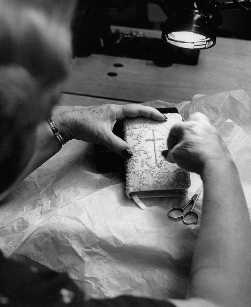A woman puts the finishing touches on the pearl-studded prayer book for Grace Kelly's wedding, Hollywood, Calif., 1956.